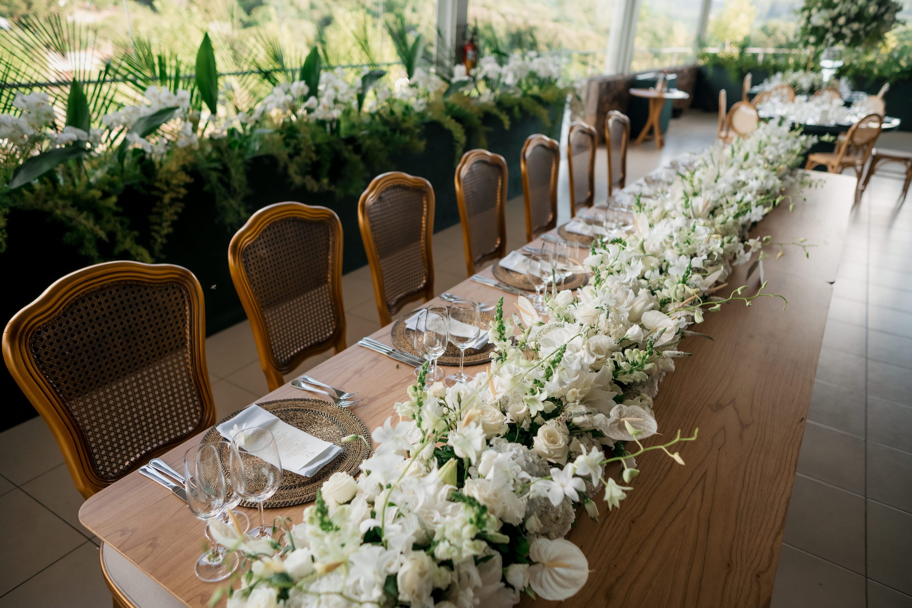 Longue table de réception décorée d'un chemin de fleurs blanches par un décorateur de mariage