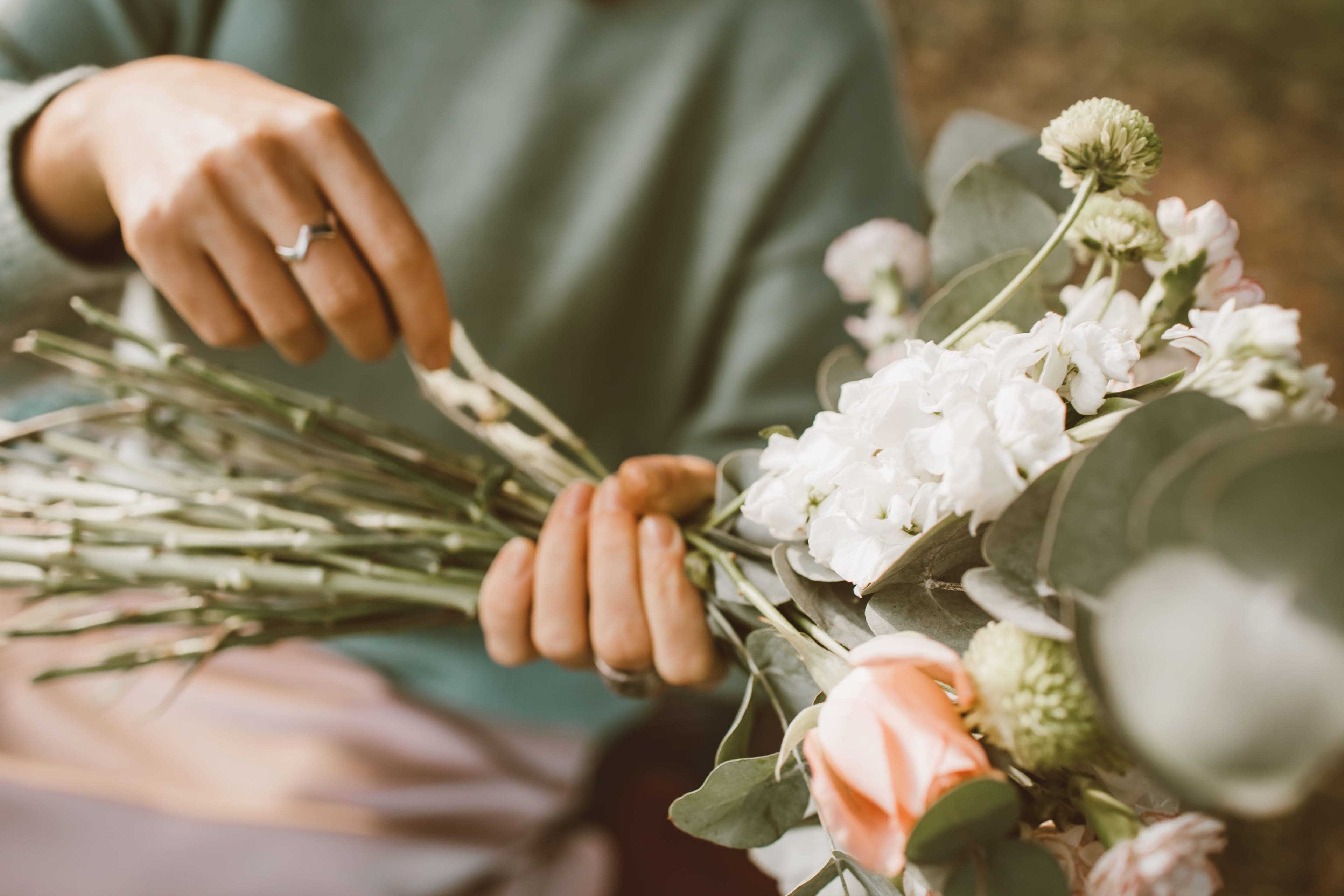 Fleuriste de mariage composant un bouquet de fleurs blanches et pêche