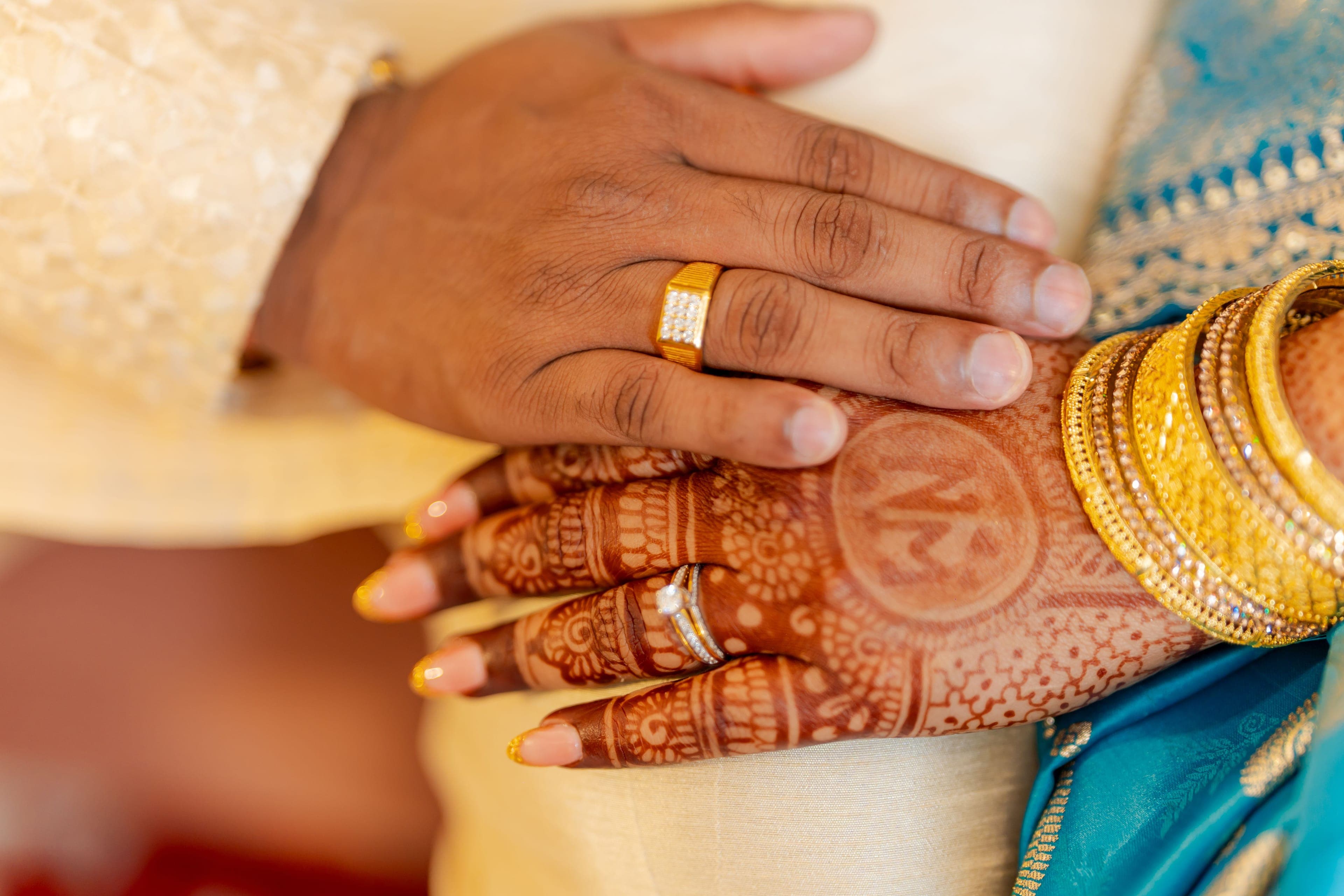 Mains des mariés, la mariée ornée de henné et de bracelets dorés, mariage franco-indien