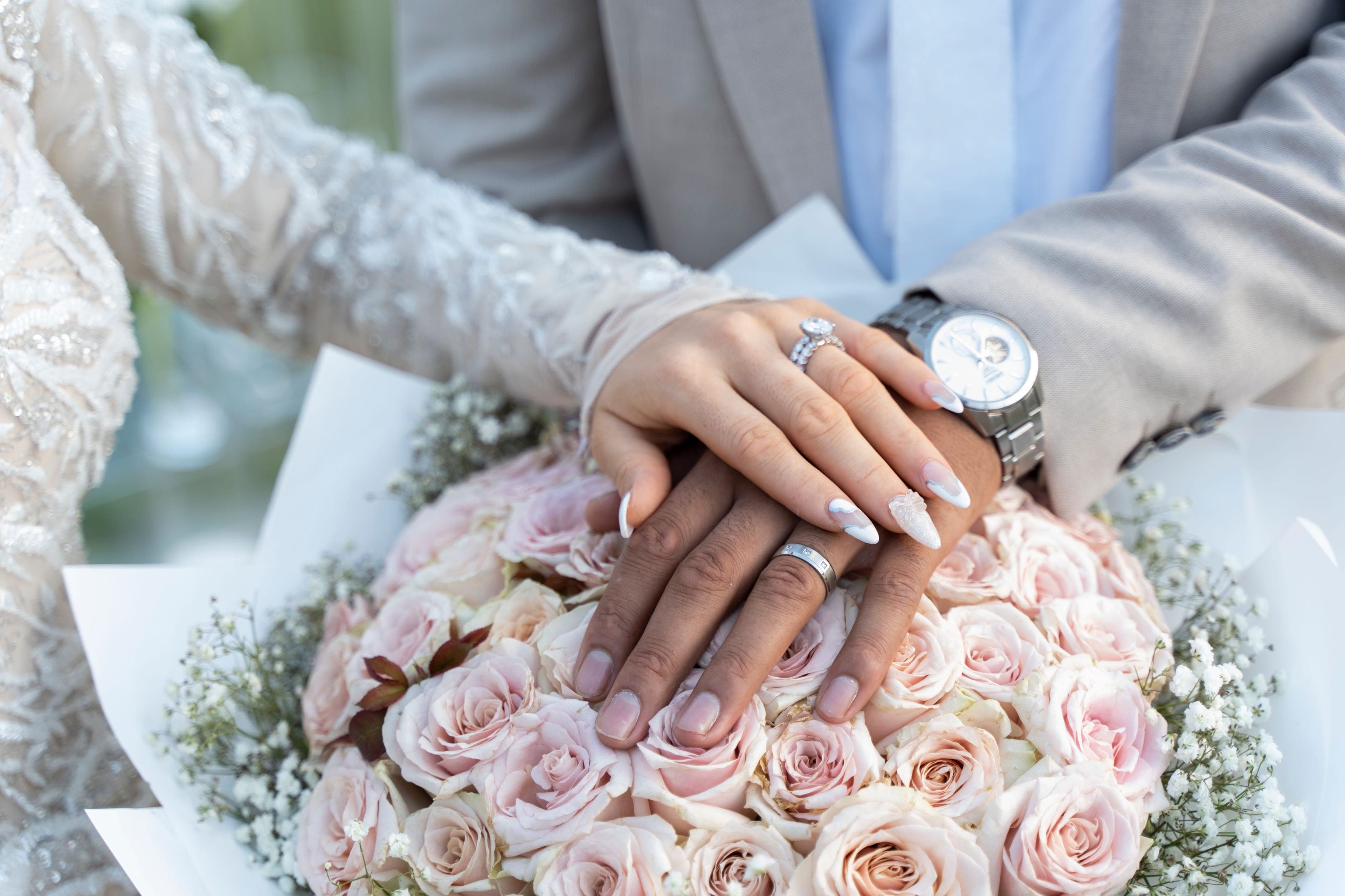Mains des mariés et alliances sur un bouquet de roses, mariage libanais
