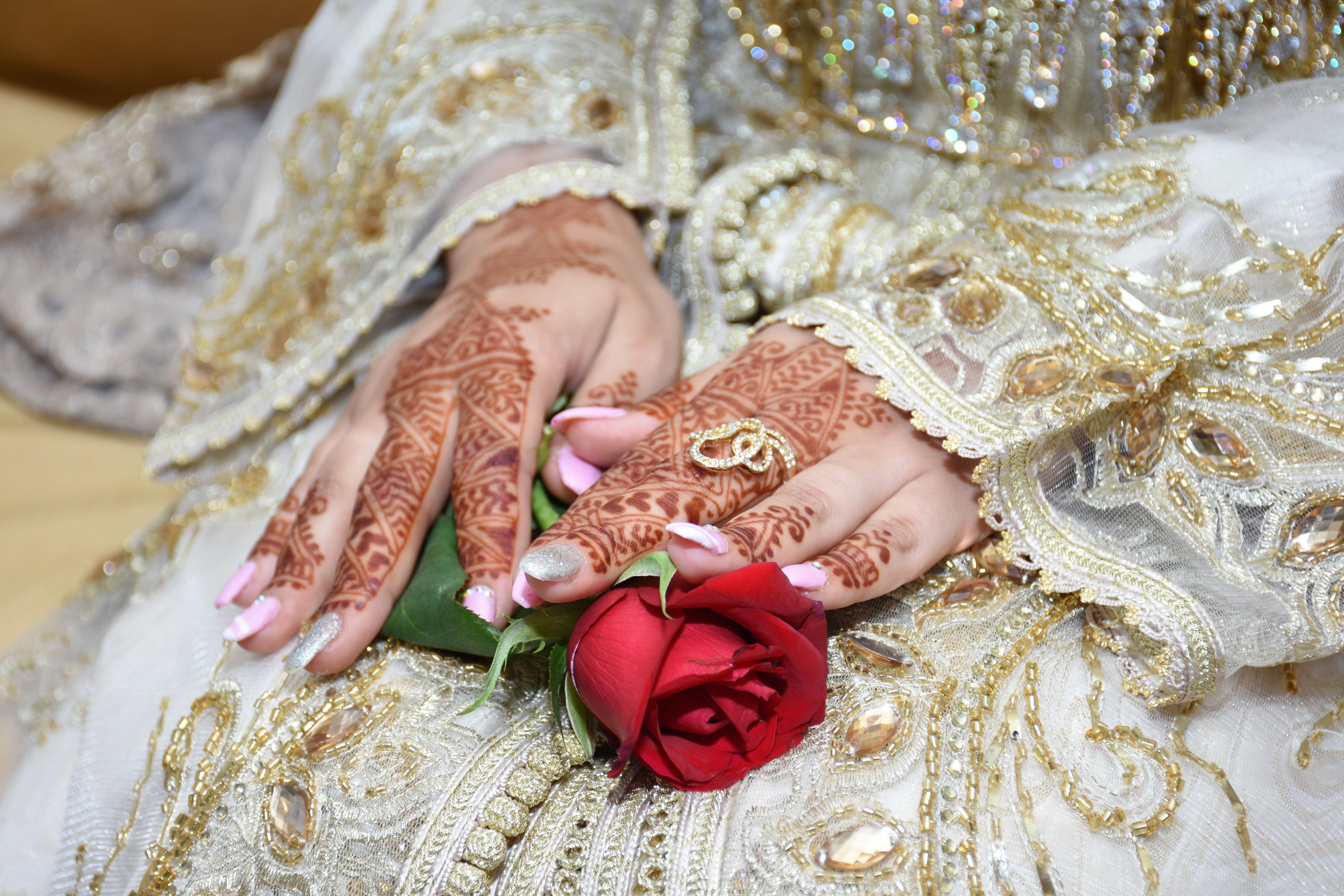 Mains de la mariée ornées de henné sur un caftan brodé, mariage marocain