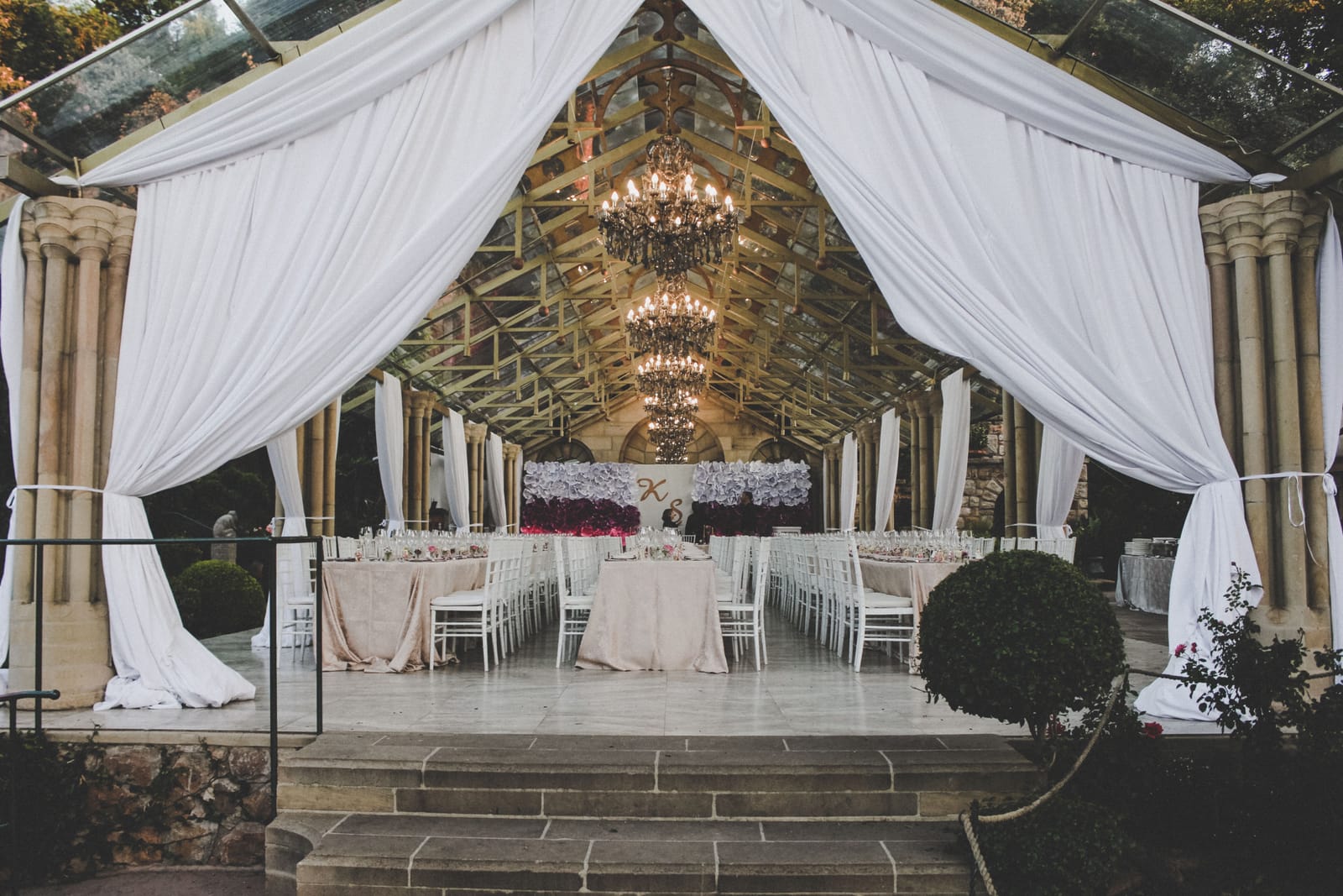 Salle de réception de mariage habillée de tentures blanches et de lustres, vue depuis l'entrée