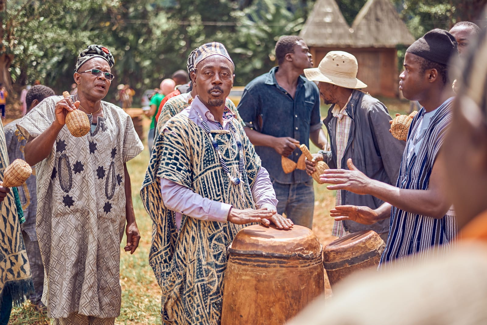 Percussionnistes vêtus de tissus indigo à motifs, jouant sur de grands tambours de bois lors d'une fête à Batoufam, au Cameroun