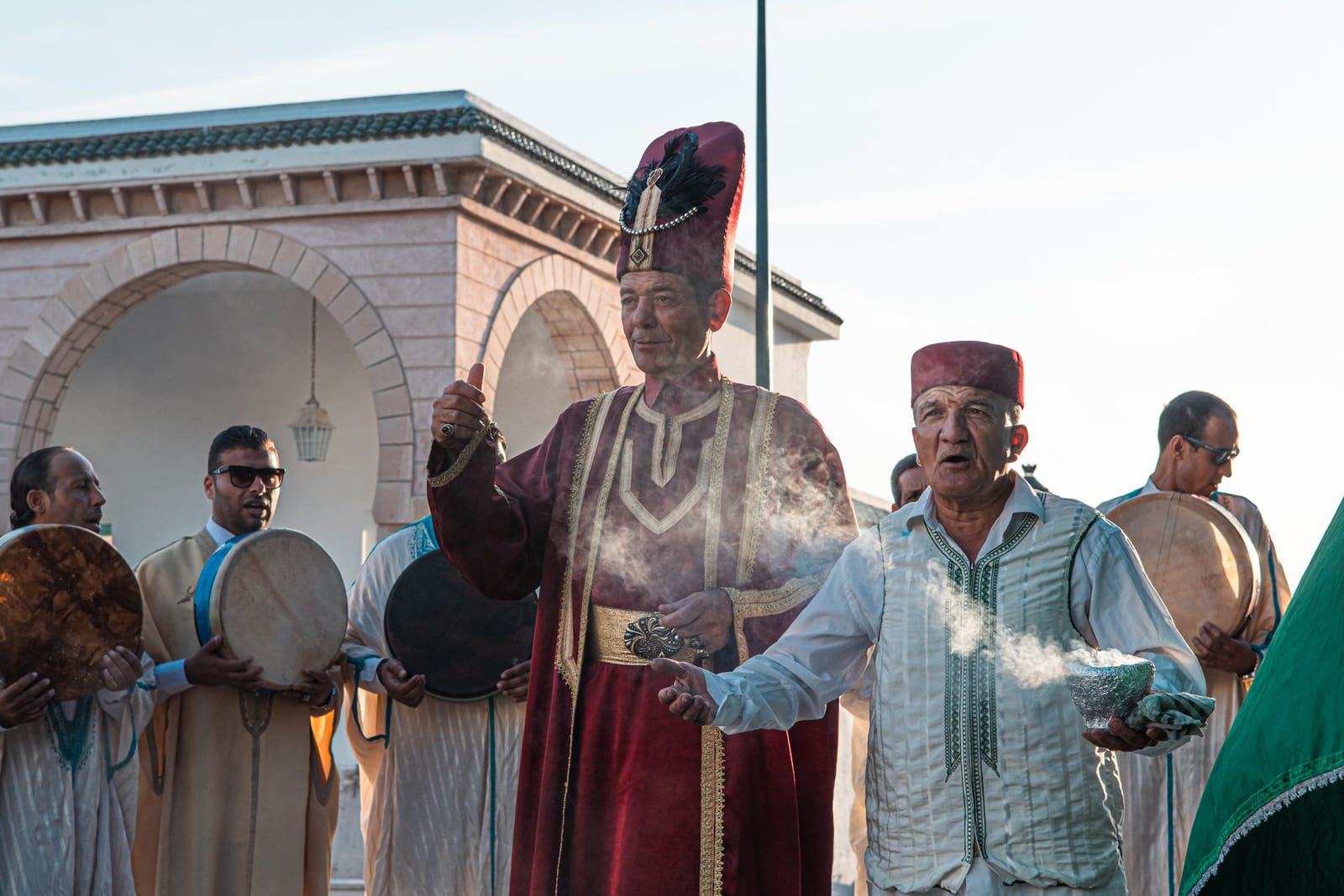 Musiciens tunisiens avec des bendirs et un homme en tenue traditionnelle rouge, lors d'un rassemblement à La Marsa
