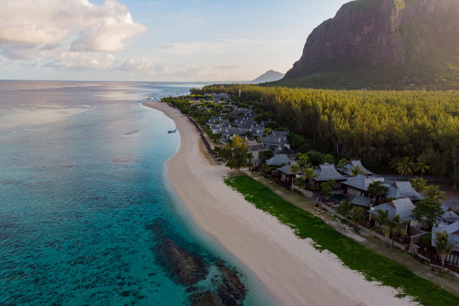 Vue aérienne d'une plage de sable blanc bordée d'un hôtel et d'un lagon turquoise, au pied du Morne Brabant à Maurice