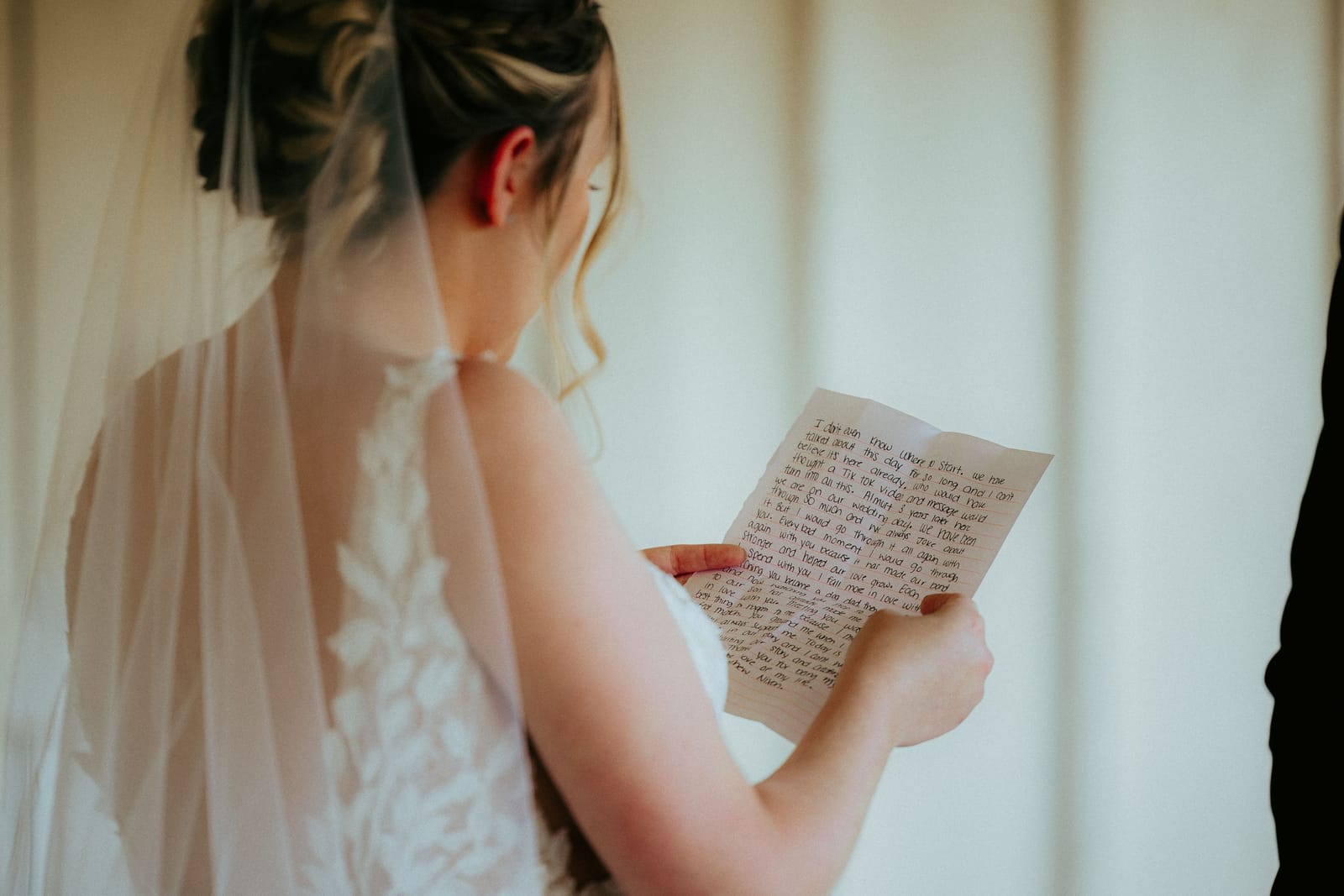 Une mariée en robe de dentelle relit un texte écrit à la main avant la cérémonie