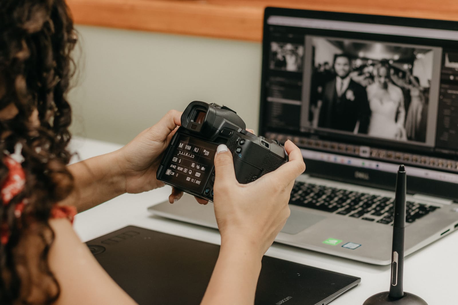 Photographe vérifiant les réglages de son appareil devant un ordinateur affichant une photo de mariage